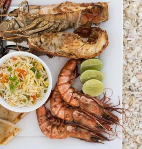 a plate of food with seafood and a bowl of coleslaw at Casa Carlotta & Villa in Nungwi