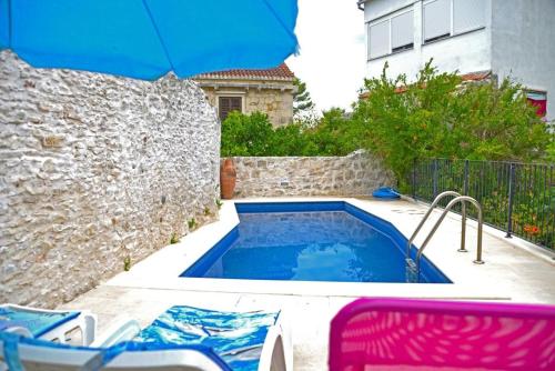 a swimming pool with an umbrella next to a building at Family friendly apartments with a swimming pool Sutivan, Brac - 14737 in Sutivan