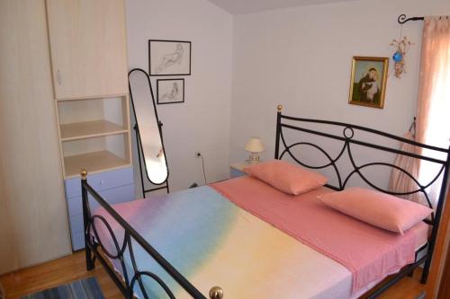 a bedroom with a bed with pink pillows on it at Family friendly apartments with a swimming pool Sutivan, Brac - 14737 in Sutivan
