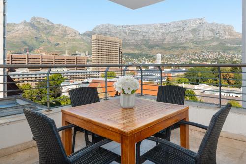 een tafel met stoelen en een vaas met bloemen op een balkon bij Mandela Rhodes Luxury Apartments in Kaapstad