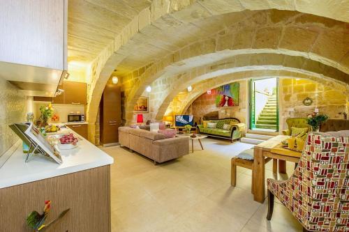 a kitchen and a living room with a stone wall at The Valley Holiday Home in Kerċem