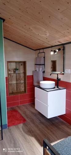 La salle de bains est pourvue d'un lavabo blanc et d'un mur rouge. dans l'établissement Douar ha mor, à Locoal-Mendon