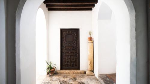 un pasillo con una puerta negra en una pared blanca en Apartamento en Palacete Cordobés S. XVIII / Judería de Córdoba en Córdoba