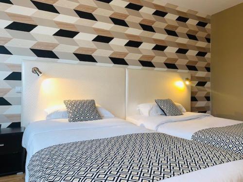 two beds sitting next to each other in a bedroom at Grand Hôtel de Nîmes 4 étoiles in Nîmes