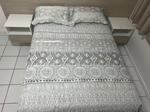 a bed with a gray and white comforter on it at NEO 1.0 in Maceió