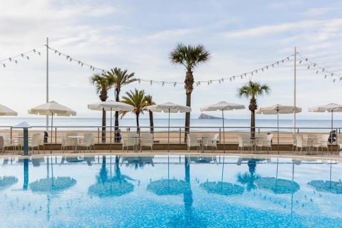 a wedding at the beach with a swimming pool and palm trees at Hotel Cimbel in Benidorm