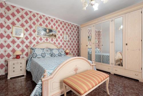 1 dormitorio con cama blanca y papel pintado de color rosa en Ático Andrea, en Caleta de Interián