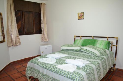 Un dormitorio con una cama verde con toallas. en Pousada Rosa dos Ventos en Genipabu