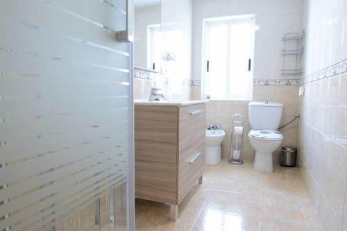 a white bathroom with a toilet and a sink at DOMUS SALAMANCA EDISSON in Salamanca