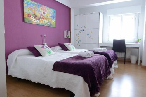 two beds in a bedroom with a purple wall at DOMUS SALAMANCA EDISSON in Salamanca