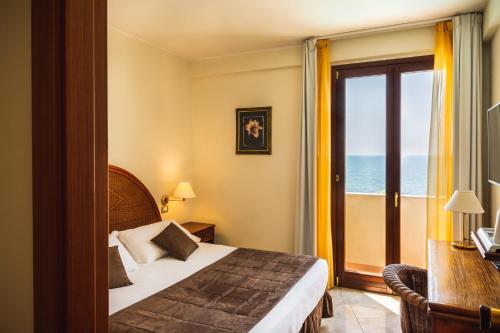 a bedroom with a bed and a window with the ocean at Hotel Ara Solis in Lido Azzurro