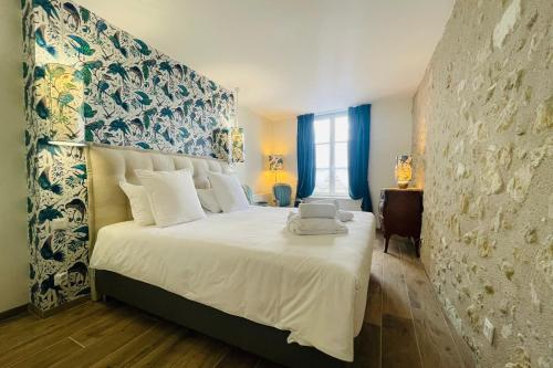 a bedroom with a large white bed with a wall at Splendid apartment at the foot of the castle of Amboise - View of the Loir in Amboise