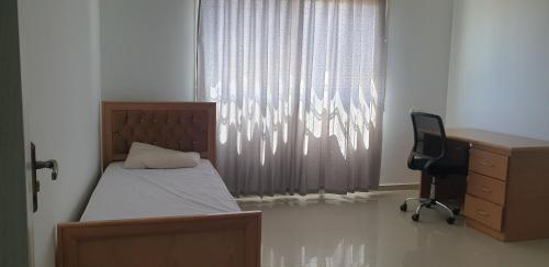 - une chambre avec un lit, un bureau et une chaise dans l'établissement Nice Apartment in Hebron Palestine, à Khirbat an Naşārá