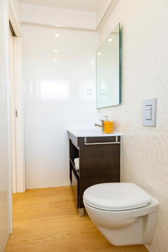 a bathroom with a white toilet and a sink at The Modern 1385 Apartment in Batalha