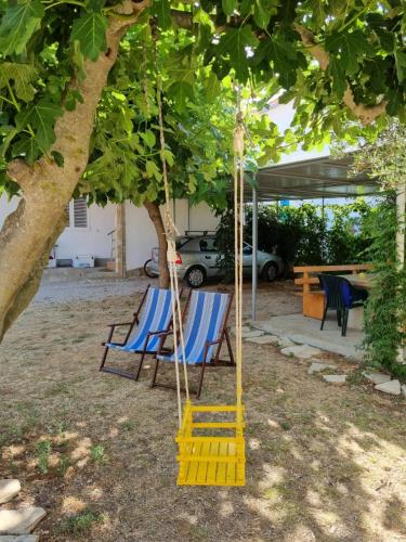 a yellow swing under a tree in a yard at Family friendly seaside apartments Nevidjane, Pasman - 325 in Neviđane