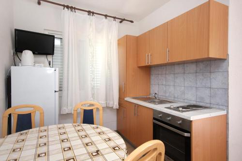 a kitchen with a table and a white refrigerator at Seaside apartments with a swimming pool Viganj, Peljesac - 260 in Viganj