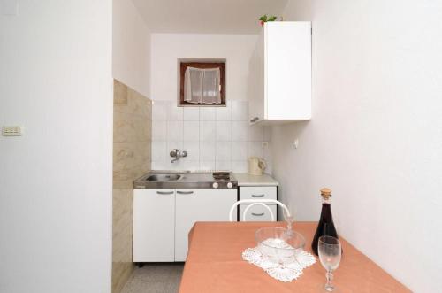 a small kitchen with a table with a bottle of wine at Apartments and rooms by the sea Zuljana, Peljesac - 256 in Žuljana