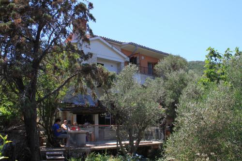 a man sitting at a table in front of a house at Apartments by the sea Valun, Cres - 386 in Valun