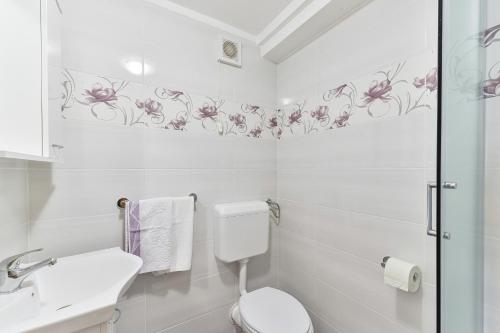 een witte badkamer met roze bloemen op de muur bij Apartments and rooms by the sea Tkon, Pasman - 336 in Tkon