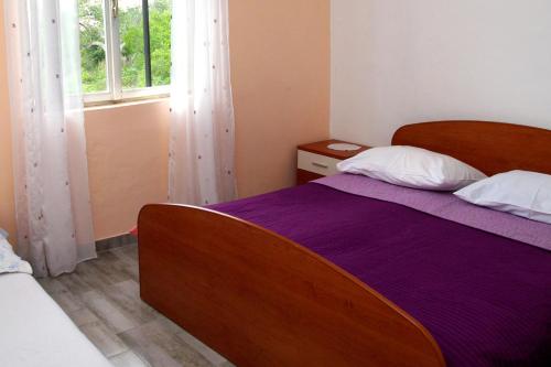 a bedroom with a bed with purple sheets and a window at Secluded fisherman's cottage Cove Zuborovica, Pasman - 322 in Mrljane