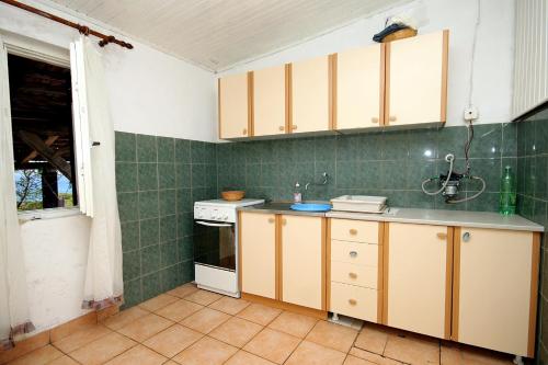 a kitchen with white cabinets and green tiles at Secluded fisherman's cottage Cove Zuborovica, Pasman - 322 in Mrljane