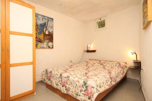 a small bedroom with a bed and a painting on the wall at Apartments by the sea Nerezine, Losinj - 330 in Nerezine