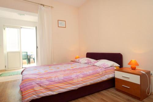 a bedroom with a bed with a night stand and a window at Apartments by the sea Mrljane, Pasman - 319 in Neviđane