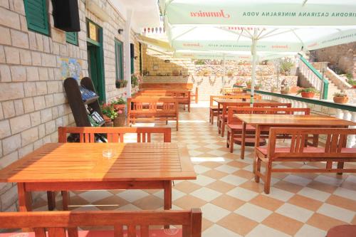 una fila di tavoli e panche in legno in un ristorante di Apartments and rooms by the sea Zaglav, Dugi otok - 393 a Sali (Sale)