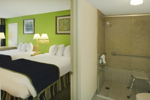 a hotel room with two beds and a shower at Days Inn by Wyndham Richmond Hill/Savannah in Richmond Hill