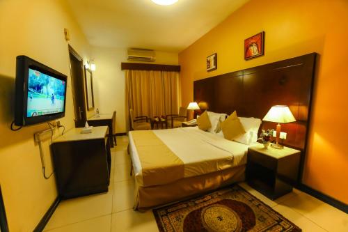 a hotel room with a bed and a flat screen tv at Hyde Park Hotel in Dubai