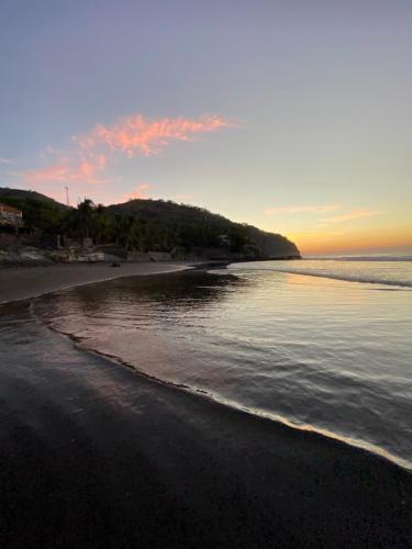 a view of a beach at sunset with the ocean at Lote 44 Guesthouse in El Zonte
