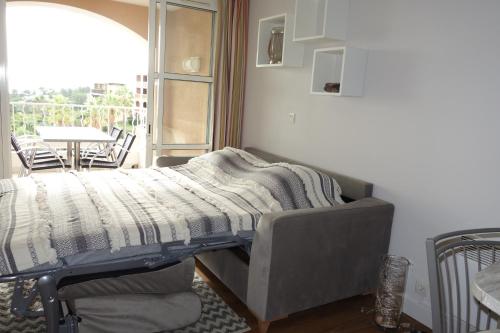 a bed with a blanket on top of it in a room at Cap Estérel Agay St Raphaël vue mer in Agay - Saint Raphael