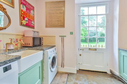 a laundry room with a washing machine and a window at Walcot Hall - Stunning Stately Home set in 27 acres of parkland and sleeping 16+ in Alkborough