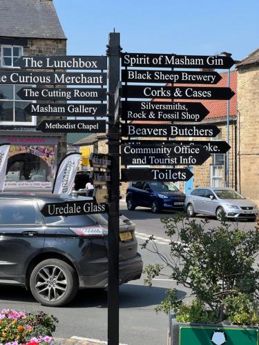 a street sign with many signs on a pole at Brewers Den in Masham