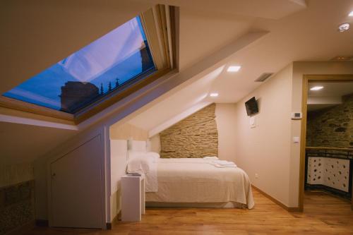 a bedroom with a bed with a large window at Hospederia Tarela in Santiago de Compostela