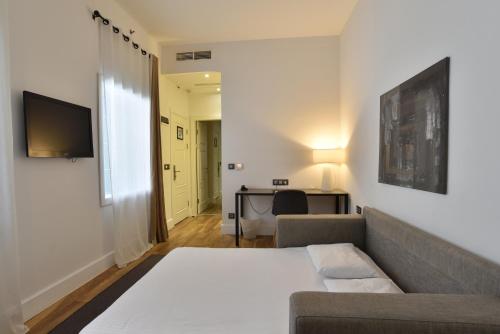a living room with a couch and a desk with a television at Hotel Zenit Budapest Palace in Budapest
