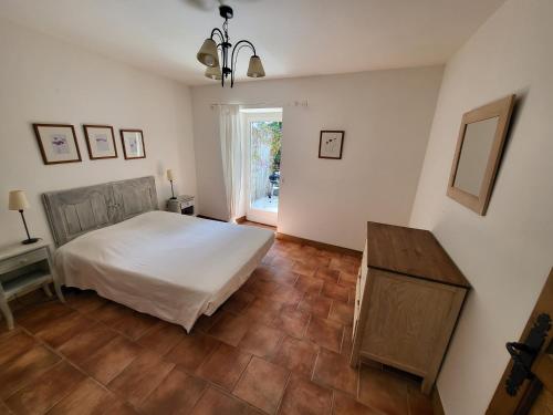 een slaapkamer met een wit bed en een houten vloer bij La petite Maison 