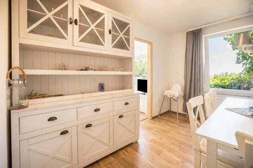 尤伊斯特的住宿－Seehaus Juist，厨房配有白色橱柜、桌子和窗户。