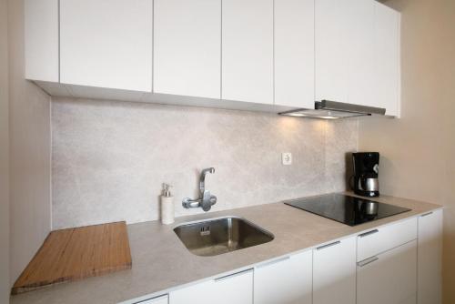 Una cocina con fregadero y gabinetes blancos. en Apartamento Royal Park Albatros, en San Miguel de Abona
