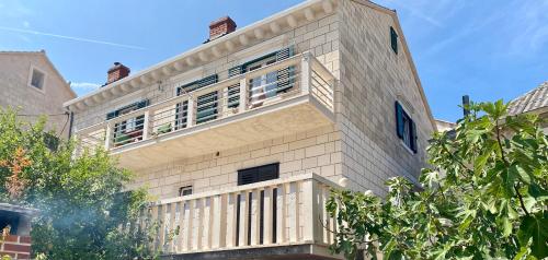 a white brick building with a balcony on it at Apartment Olga in Pučišća