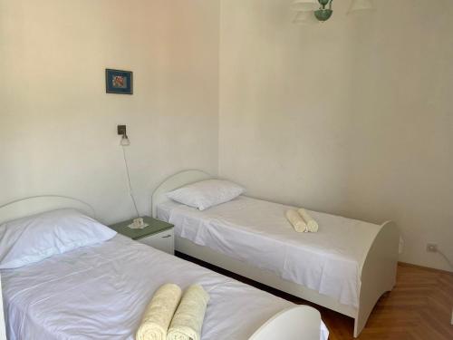 two beds in a room with white sheets at Apartment Olga in Pučišća
