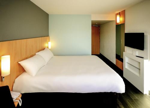 a bedroom with a large white bed and a television at ibis Avignon Centre Gare in Avignon