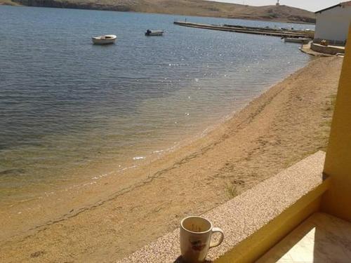 a cup of coffee sitting on a ledge next to a beach at Studio Dinjiska 9386a in Povljana