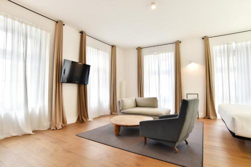 a living room with a couch and a chair and a tv at Hotel Zenit Budapest Palace in Budapest