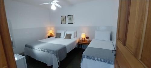 a room with two beds and a desk with two lamps at Pousada da Vila in Itaipava