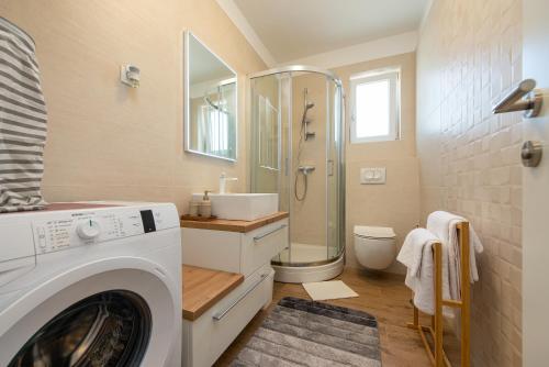 uma casa de banho com uma máquina de lavar roupa e um lavatório em La Prima Privlaka Luxury Apartments I em Privlaka