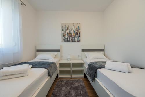 Duas camas num quarto com paredes brancas em La Prima Privlaka Luxury Apartments I em Privlaka