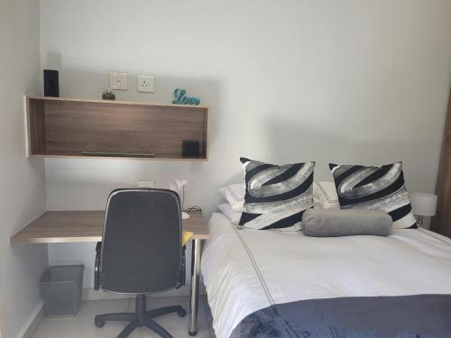 1 dormitorio con cama, escritorio y silla en Ollies en Pretoria