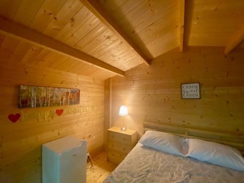 a bedroom with a bed in a wooden cabin at Algonquin Madawaska Lodge Cottage Glamping Cabins in Madawaska
