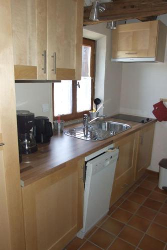 une cuisine avec des armoires en bois et un évier dans l'établissement Les Pins - Maison avec parking ferme et jardin commun au calme, à Saint-Prix
